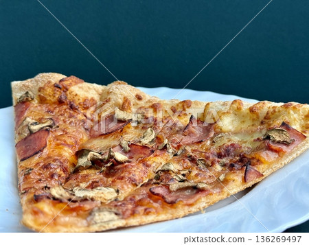 A close-up shot of a large classic pizza with cheese, ham, and mushrooms. A delicious, nutritious, and quick meal. 136269497