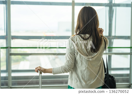 A woman looking out the window at the airport. Photo courtesy of Kansai International Airport (KIX). 136270052