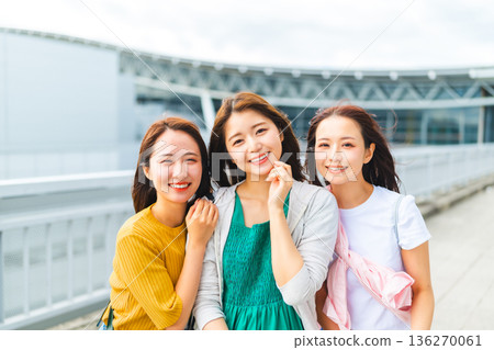 Three women laughing at the airport ■Photography cooperation: Kansai International Airport (KIX) 136270061