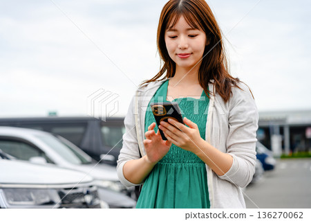 A woman using her smartphone in a parking lot. Photo courtesy of Kansai International Airport (KIX) A woman using her smartphone in a parking lot. Photo courtesy of Kansai International Airport (KIX) 136270062