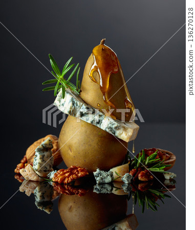 Gorgonzola with honey, pear, walnuts, and rosemary on a black background. 136270128