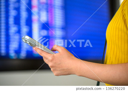 一名女子在機場查看她的智慧型手機。照片由關西國際機場(KIX)提供。 一名女子在機場查看她的智慧型手機。照片由關西國際機場(KIX)提供。 136270220