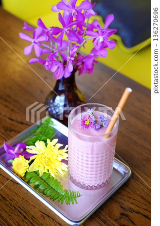 Top view of a glass of blueberries smoothie and violet flowers decorated on topping Top view of a glass of blueberries smoothie and violet flowers decorated on topping 136270696