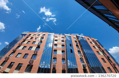 The blue sky with clouds is reflected in the glass facade of the house The blue sky with clouds is reflected in the glass facade of the house 136270720