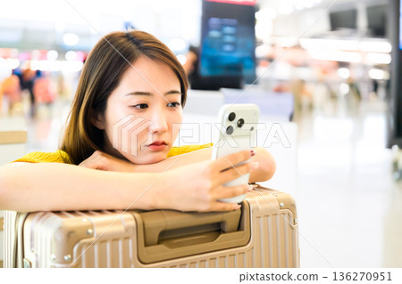 A woman looking at her smartphone at the airport. Photo courtesy of Kansai International Airport (KIX). 136270951