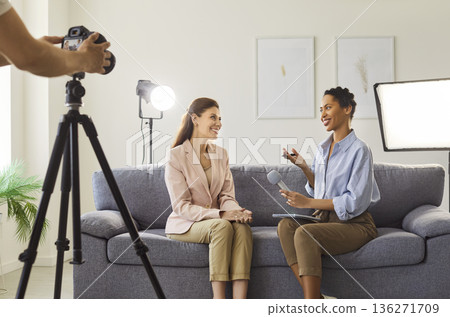 Woman journalist conducting interview sitting on sofa and recording broadcast 136271709