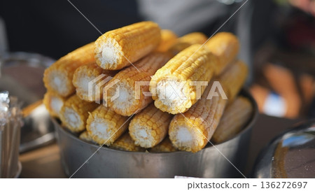 Boiled yellow corn cobs piled in a container, a popular street food snack in India 136272697