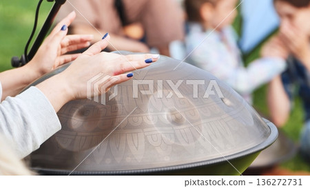 Hands playing percussion hang drum in nature for meditation and sound healing Hands playing percussion hang drum in nature for meditation and sound healing 136272731