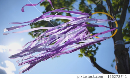 Purple and white ribbons flowing in wind against blue sky and bright sun Purple and white ribbons flowing in wind against blue sky and bright sun 136272741