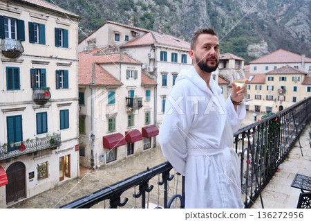 Man in white bathrobe posing on balcony in historic old town Man in white bathrobe posing on balcony in historic old town 136272956