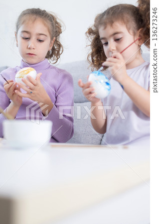 Two sisters decorating Easter eggs. Two sisters decorating Easter eggs. 136273246
