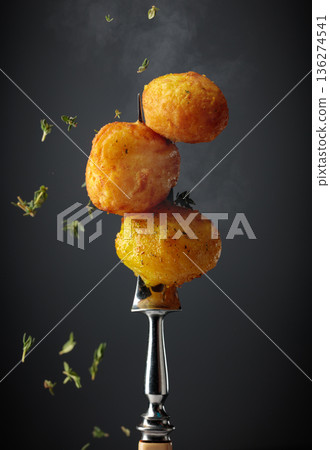 Roasted potatoes on a fork, sprinkled with a fresh thyme. 136274541