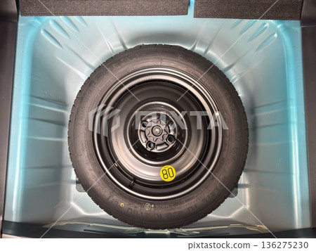 A spare tire stored directly opposite the trunk floor of a car A spare tire stored directly opposite the trunk floor of a car 136275230