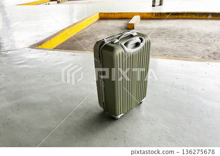 forgotten olive green hard shell suitcase on empty concrete terminal floor 136275678