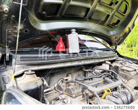 engine oil plastic bottle with red funnel cap on open car hood for maintenance engine oil plastic bottle with red funnel cap on open car hood for maintenance 136275680
