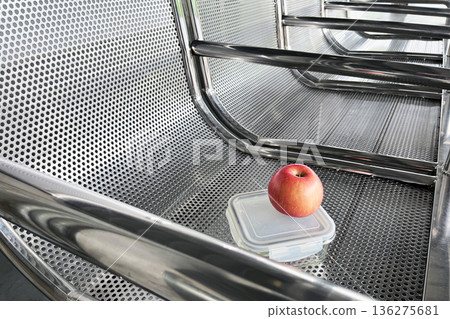 healthy snack on the go with red apple and glass lunch box on perforated metal bench at transit station healthy snack on the go with red apple and glass lunch box on perforated metal bench at transit station 136275681