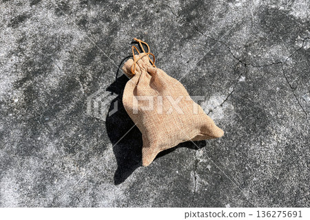 small burlap jute drawstring bag on cracked concrete background for rustic gift packaging small burlap jute drawstring bag on cracked concrete background for rustic gift packaging 136275691