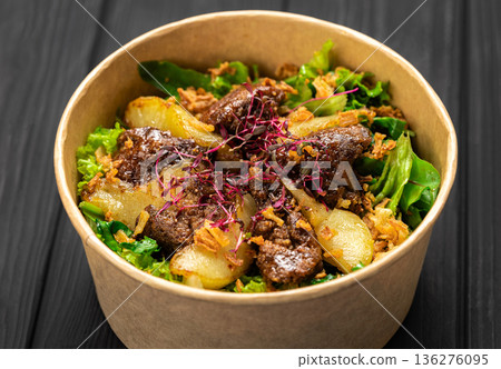 Warm liver salad with caramelized pear, mixed greens and crispy onions in kraft bowl 136276095