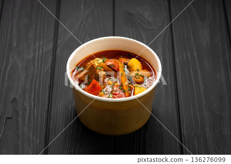 Hungarian bograch goulash soup with beef and vegetables in kraft bowl on dark wooden table 136276099