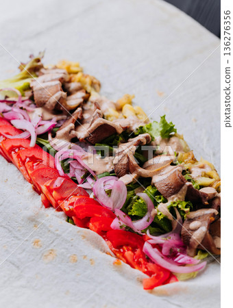Open pork shawarma wrap with tomatoes, pickled onions and sauce, top view Open pork shawarma wrap with tomatoes, pickled onions and sauce, top view 136276356