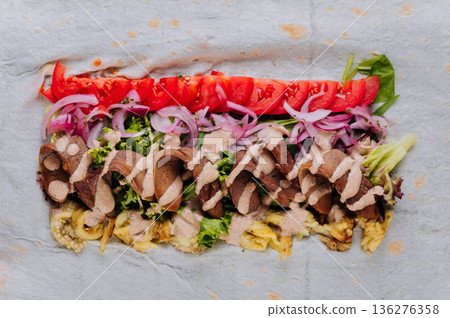 Open pork shawarma wrap with tomatoes, pickled onions and sauce, top view 136276358