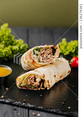 Grilled tuna tortilla wraps with greens, sauce and tomatoes on slate 136276361