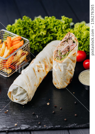 Pork shawarma wraps with fries and ketchup sauce on black table, close up Pork shawarma wraps with fries and ketchup sauce on black table, close up 136276365