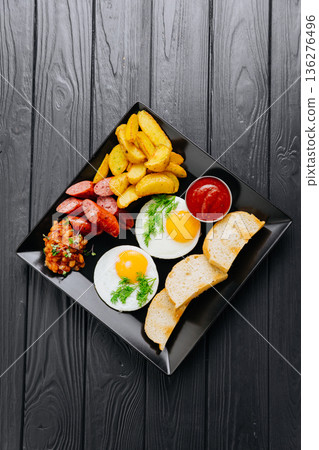 Breakfast plate with fried eggs, sausage, potato wedges and bread, top view Breakfast plate with fried eggs, sausage, potato wedges and bread, top view 136276496