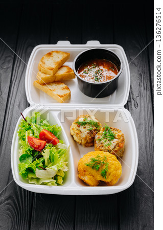 Takeaway lunch box with tomato soup, salad and cutlets on dark wooden table Takeaway lunch box with tomato soup, salad and cutlets on dark wooden table 136276514
