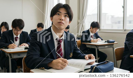 A male high school student facing his notebook while taking a class in the classroom 136276542