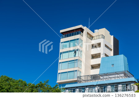 Window cleaner man cleansing on high building against blue sky, Fukuoka Window cleaner man cleansing on high building against blue sky, Fukuoka 136276583