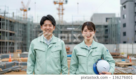 微笑的男女工人們並肩站在建築工地上。 微笑的男女工人們並肩站在建築工地上。 136276801