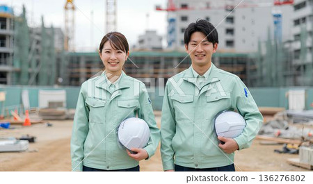在建築工地,微笑的男女工人們戴著安全帽排成一列。 在建築工地,微笑的男女工人們戴著安全帽排成一列。 136276802