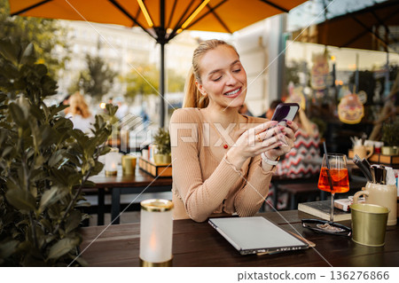 Young woman smiling using smartphone at outdoor cafe in Vienna Young woman smiling using smartphone at outdoor cafe in Vienna 136276866