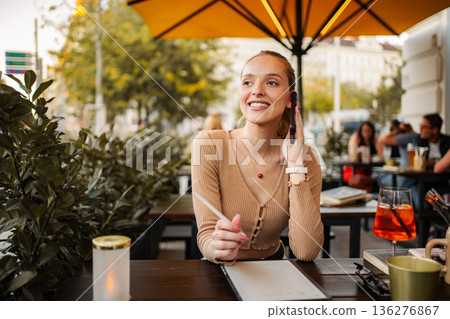Young woman enjoying call and drink at outdoor Vienna cafe 136276867