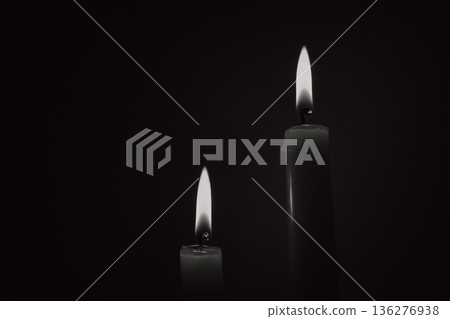 Two burning candles in black and white style, mourning concept or energy blackout background, symbol of memory and light during darkness 136276938