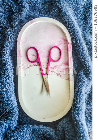 Manicure and self-care concept. Pink nail scissors on a decorative marble tray, set on a soft blue towel. Top view. 136276985