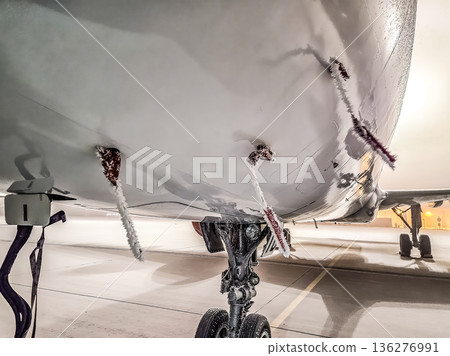 icy aircraft on a winter tarmac. Frozen Remove Before Flight tags and landing gear in freezing weather. 136276991