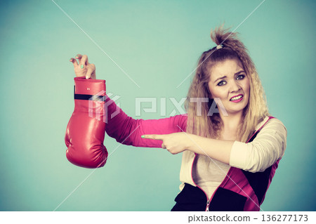 Disgusted woman holding boxing glove Disgusted woman holding boxing glove 136277173