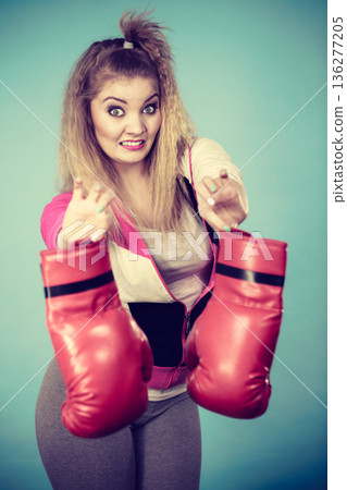 Disgusted woman holding boxing glove 136277205