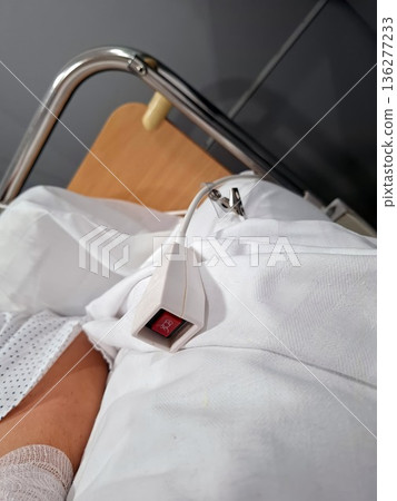 A close view of a nurse call button located on a patient's bed in a clinic. The alert device is positioned to enable easy access for the patient to request help from medical staff. A close view of a nurse call button located on a patient's bed in a clinic. The alert device is positioned to enable easy access for the patient to request help from medical staff. 136277233