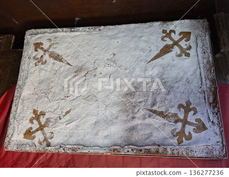 Tarta de Santiago sits on a wooden surface with powdered sugar and a stencil design. Almond cake is rectangular and decorated with sugar patterns typical of Spain. 136277236