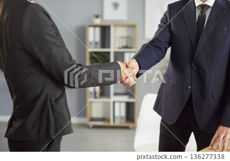 Two business professionals shaking hands in office after successful meeting and making agreement. Two business professionals shaking hands in office after successful meeting and making agreement. 136277338