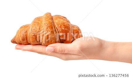 Fresh croissant on female hand isolated on white background 136277456