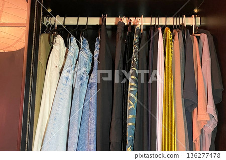 A neatly organized closet filled with various clothes on hangers A neatly organized closet filled with various clothes on hangers 136277478