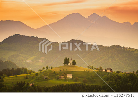 Sveti Tomaz, Slovenia. Hilltop church framed by panoramic countryside landscape under dramatic skies Sveti Tomaz, Slovenia. Hilltop church framed by panoramic countryside landscape under dramatic skies 136277515