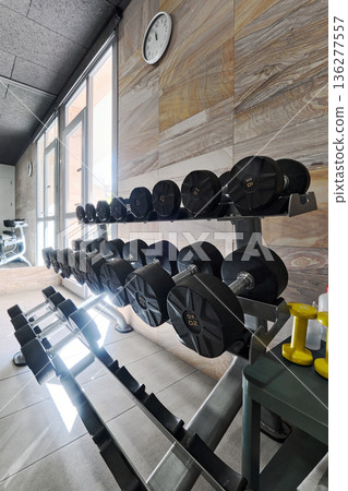 Racked dumbbells organized on stands 136277557
