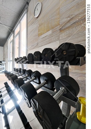 Racked dumbbells organized on stands 136277558