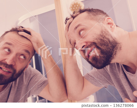 Happy adult man looking at hair in mirror Happy adult man looking at hair in mirror 136278066