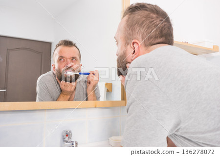 Bored guy brushing his teeth in bathroom 136278072